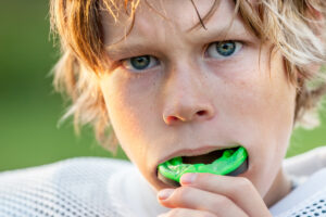 Young athlete wearing a green sports mouthguard, demonstrating proper fit and readiness for protection during sports activities.