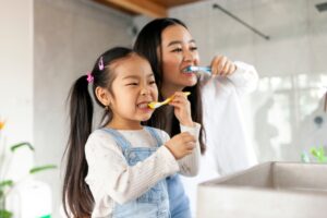 mother and daughter brushing teeth together